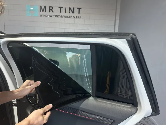 A technician at Mr Tint was removing car door glass window film.
