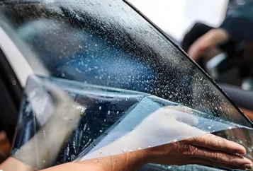 Mr Tint is applying car window film to door glass