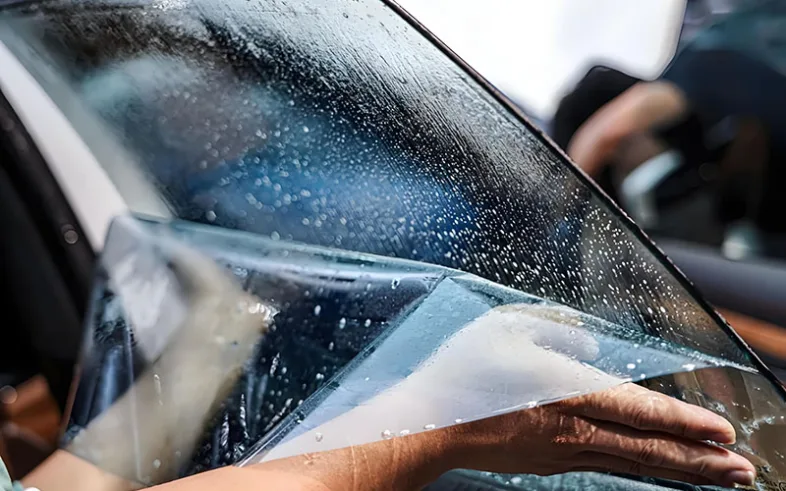 Mr Tint is applying car window film to door glass