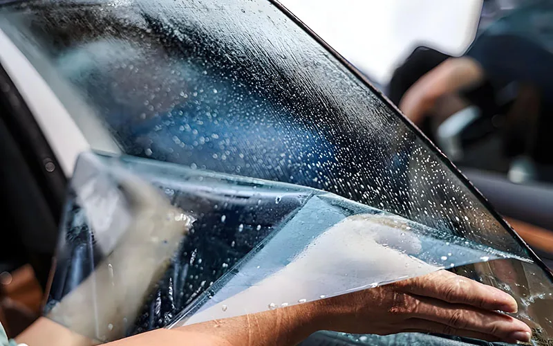 Mr Tint is applying car window film to door glass