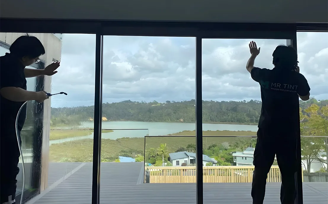 Two technicians at Mr Tint was installing window film for a house glass.